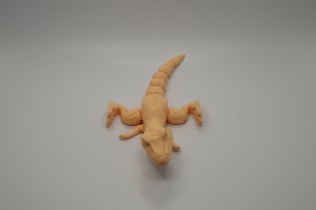 Orange dinosaur toy on a white surface with a gray background